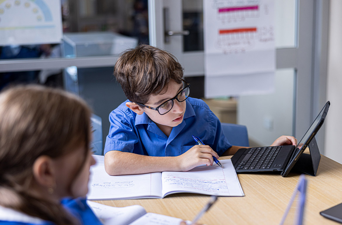 Student writing in his workbook at Our Lady of Mount Carmel Primary School Wentworthville