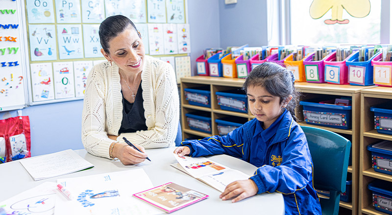 Student learning to read with her teacher in the classroom at Our Lady of Mount Carmel Primary School Wentworthville