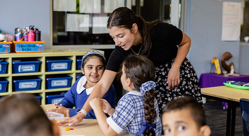 Teacher helping students in the classroom at Our Lady of Mount Carmel Primary School Wentworthville