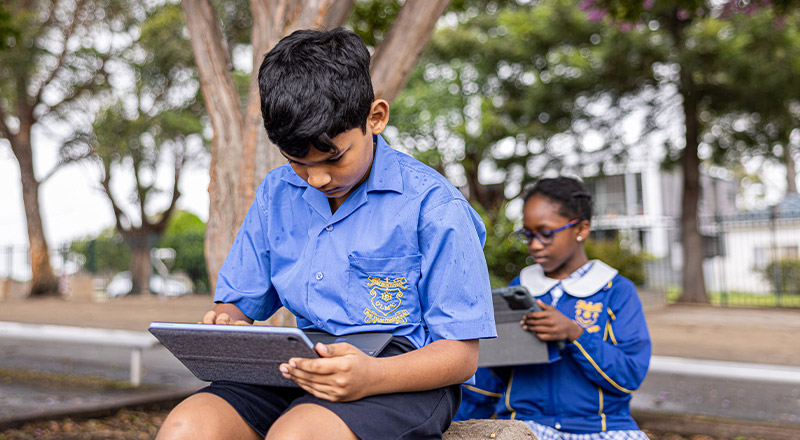 Students using their tablets outside at Our Lady of Mount Carmel Primary School Wentworthville