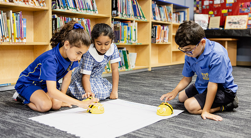 Students programming a bee bot in the library at Our Lady of Mount Carmel Primary School Wentworthville