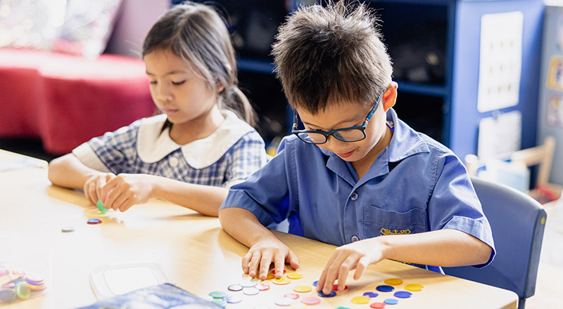 Students counting with counters at their desk at Our Lady of Mount Carmel Primary School Wentworthville