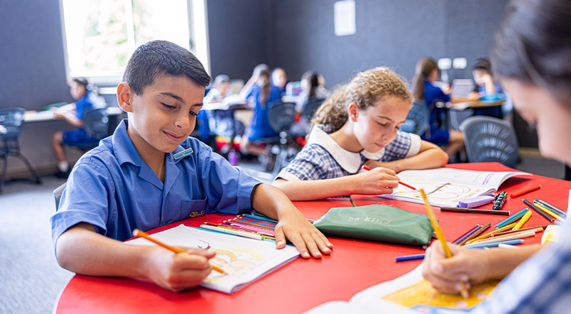 Students at their desk drawing in their workbooks at Our Lady of Mount Carmel Primary School Wentworthville