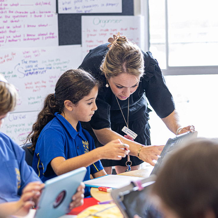 Teacher helping student in class at Our Lady of Mount Carmel Primary School Wentworthville