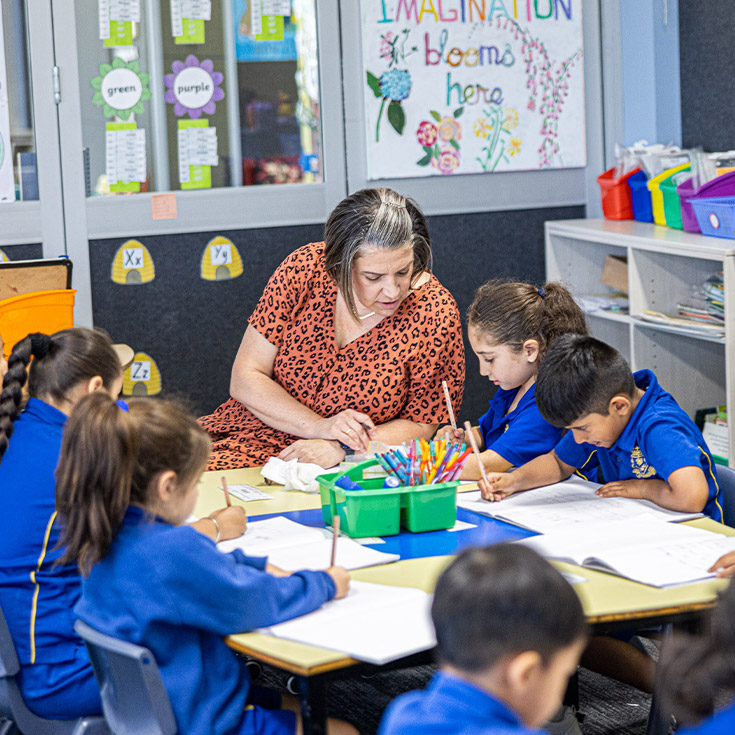 Teacher sitting with students in the classroom at Our Lady of Mount Carmel Primary School Wentworthville