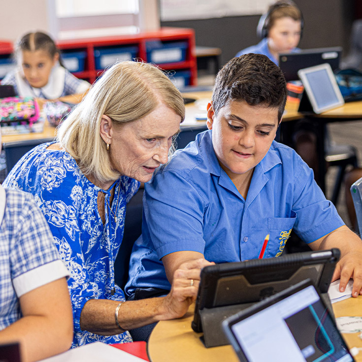 Teacher helping student in the classroom at Our Lady of Mount Carmel Primary School Wentworthville